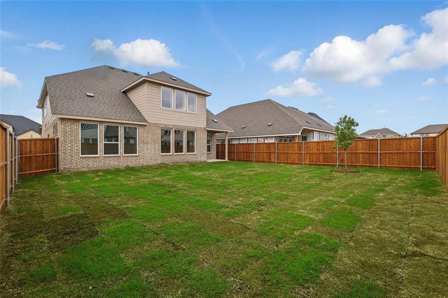Rear view of property featuring a yard, a shingled roof, brick siding, and a fenced backyard Rear view of property featuring a yard, a shingled roof, brick siding, and a fenced backyard