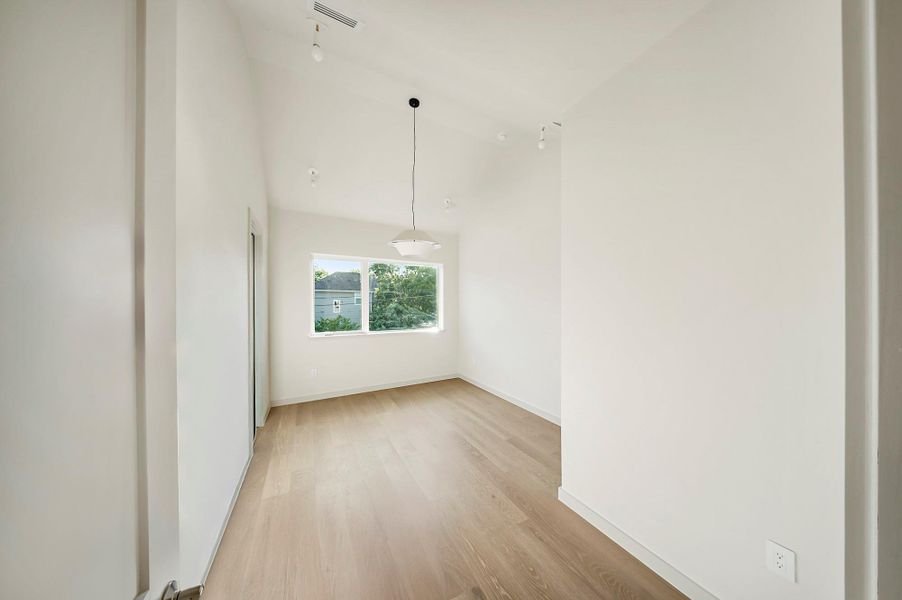 Spare room featuring light wood finished floors, vaulted ceiling, and baseboards