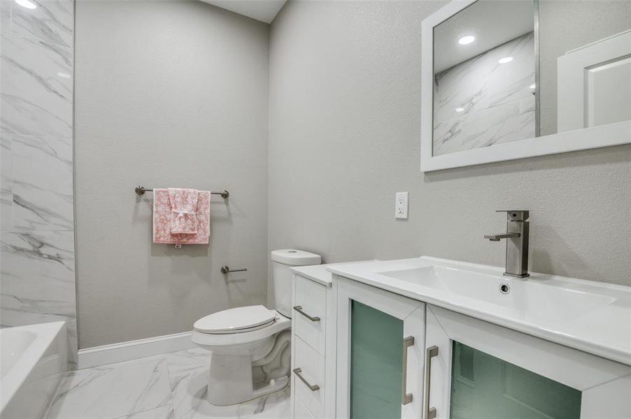 Bathroom with light marble finish floors, vanity, and bathing tub / shower combination