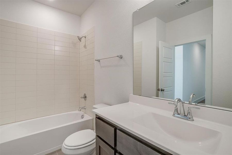 Full bathroom with oversized vanity, toilet, and tiled shower / bath combo