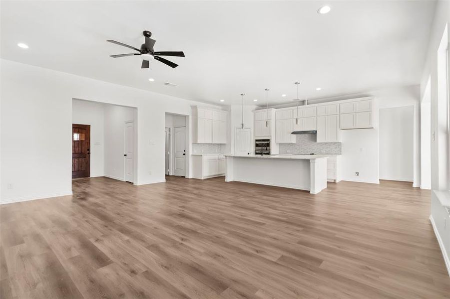 Unfurnished living room featuring ceiling fan and light hardwood / wood-style flooring