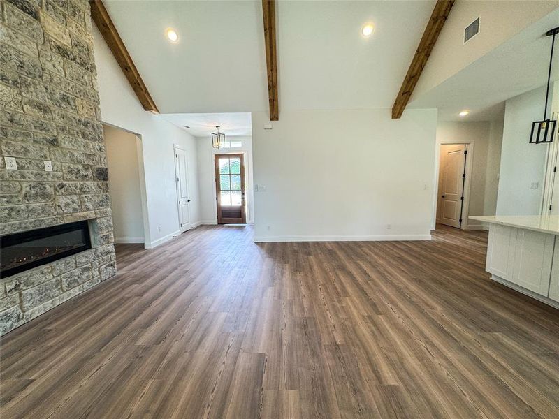 Unfurnished living room with high vaulted ceiling, beam ceiling, baseboards, a fireplace, and dark wood-style flooring Unfurnished living room with high vaulted ceiling, beam ceiling, baseboards, a fireplace, and dark wood-style flooring