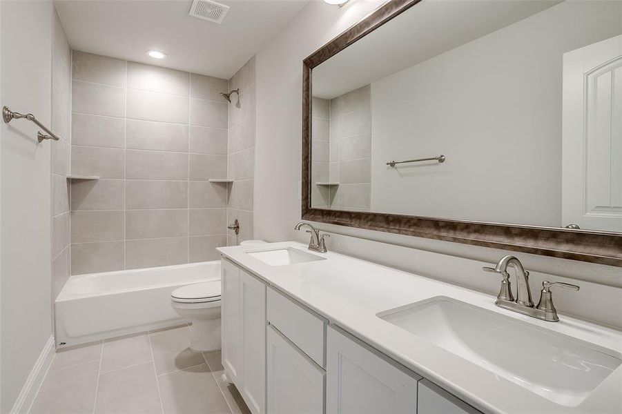 Full bathroom featuring toilet, tiled shower / bath, vanity, and tile patterned floors