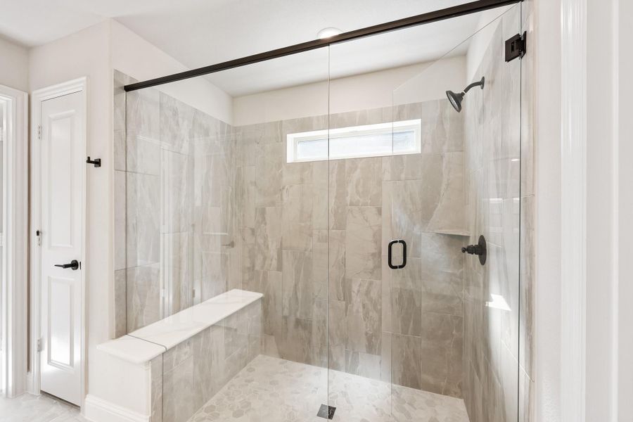 Walk-in shower with marble tile walls, built-in bench, glass door, and small window Walk-in shower with marble tile walls, built-in bench, glass door, and small window