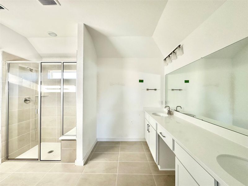Bathroom with double vanity, a stall shower, lofted ceiling, and light tile patterned flooring