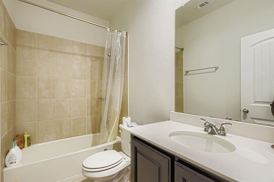 Bathroom with shower / bath combo, vanity, and a textured wall Bathroom with shower / bath combo, vanity, and a textured wall
