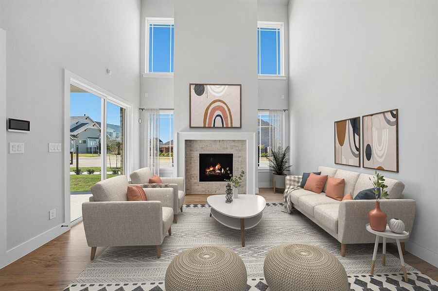 Living room featuring a towering ceiling, plenty of natural light, wood finished floors, and a lit fireplace