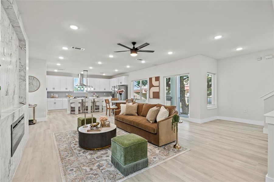Living room featuring a fireplace, light wood-style flooring, recessed lighting, and a ceiling fan Living room featuring a fireplace, light wood-style flooring, recessed lighting, and a ceiling fan