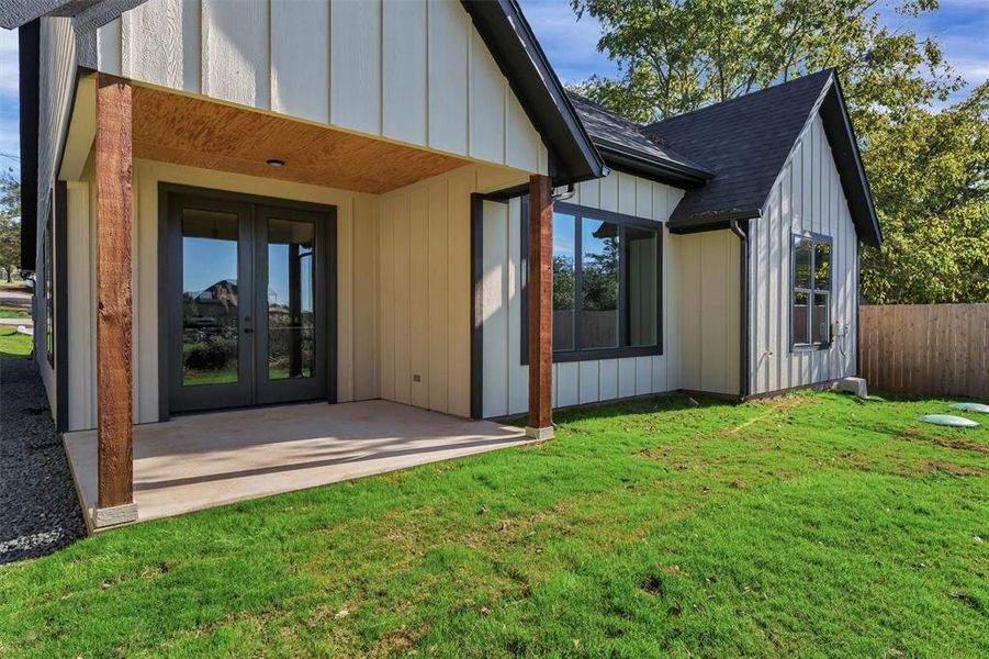 Back of house featuring board and batten siding, french doors, a shingled roof, and a patio Back of house featuring board and batten siding, french doors, a shingled roof, and a patio