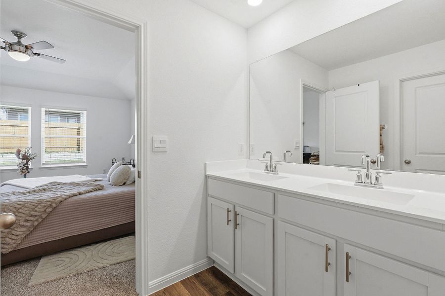 Ensuite bathroom with double vanity, dark wood-style floors, and a ceiling fan