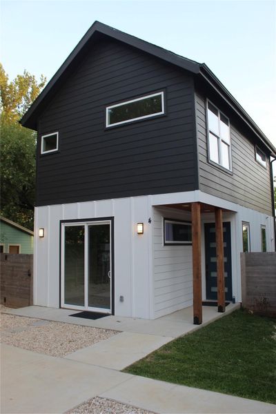 Modern home featuring striking black and white siding, an inviting entryway, and a minimalist landscaping design.