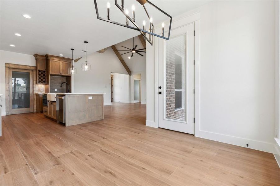 Kitchen featuring ceiling fan with notable chandelier, pendant lighting, light hardwood / wood-style flooring, tasteful backsplash, and a center island