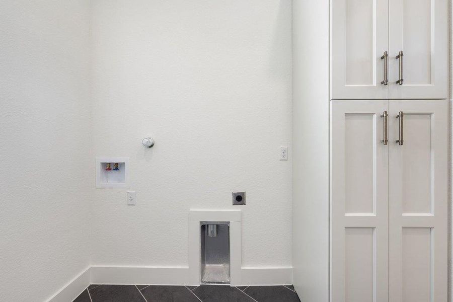 This utility area features white shaker-style cabinetry with brushed nickel hardware, providing storage solutions