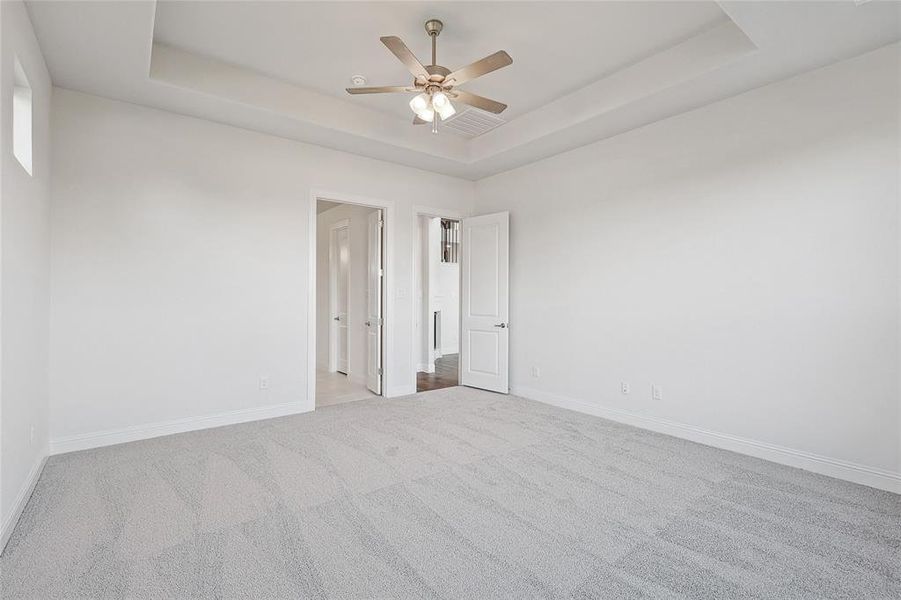 Carpeted spare room with ceiling fan and a tray ceiling