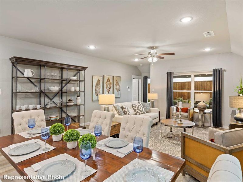Open-concept living space featuring vaulted ceilings, recessed lighting, a modern ceiling fan, and large windows with backyard views