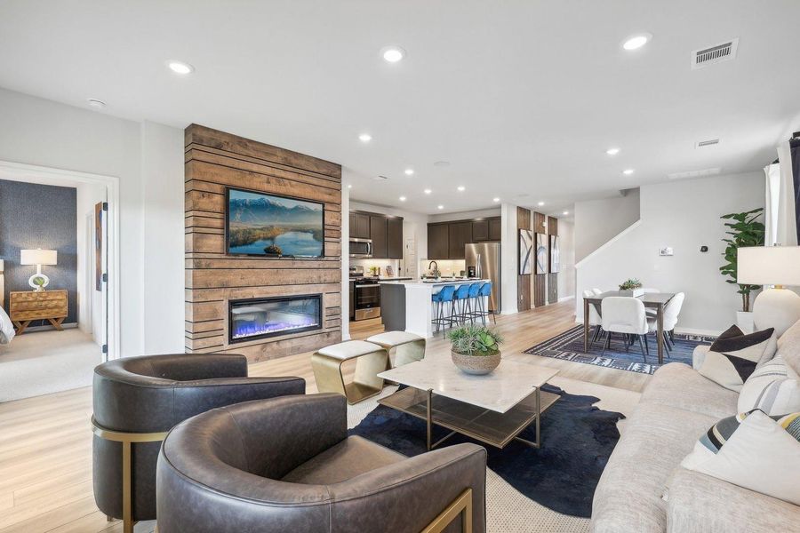 An open-concept living space features an elegant fireplace wall, seamlessly connecting to the kitchen and dining areas. An open-concept living space features an elegant fireplace wall, seamlessly connecting to the kitchen and dining areas.