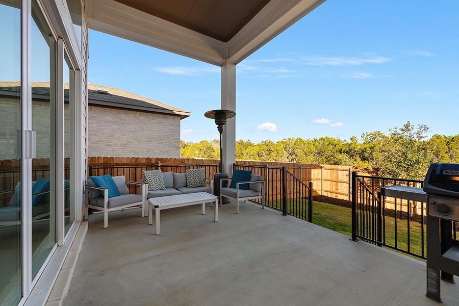 Sheltered outdoor living space looks out over a private backyard bordered by mature trees.