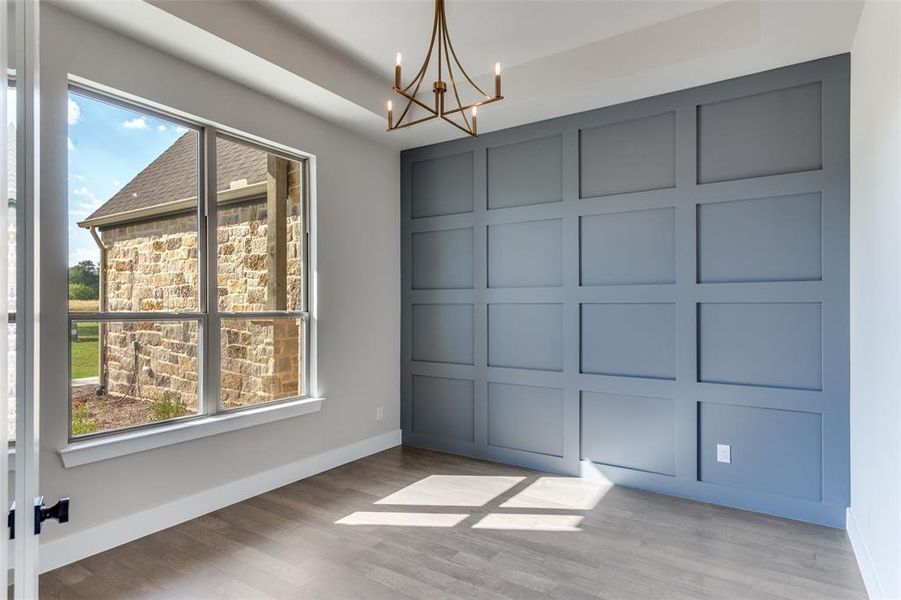 Unfurnished dining area featuring wood finished floors and a chandelier Unfurnished dining area featuring wood finished floors and a chandelier