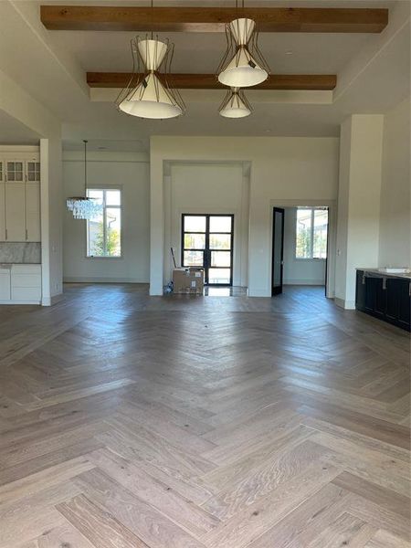 Unfurnished living room featuring light parquet flooring and beam ceiling