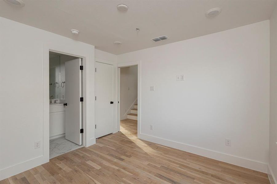 Unfurnished room with baseboards, a sink, visible vents, and light wood finished floors