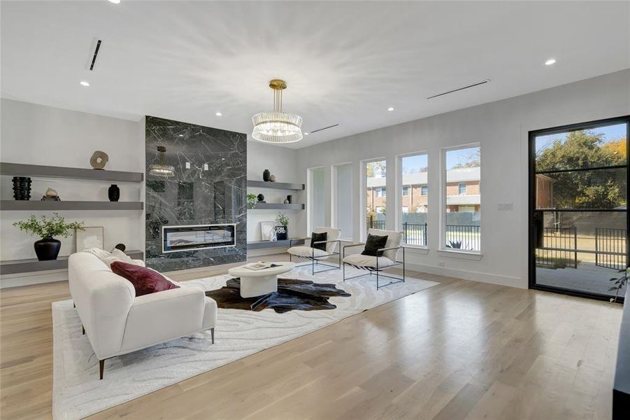 Living room featuring a high end fireplace, built in features, light hardwood / wood-style flooring, and a notable chandelier. Furniture is for staging only.