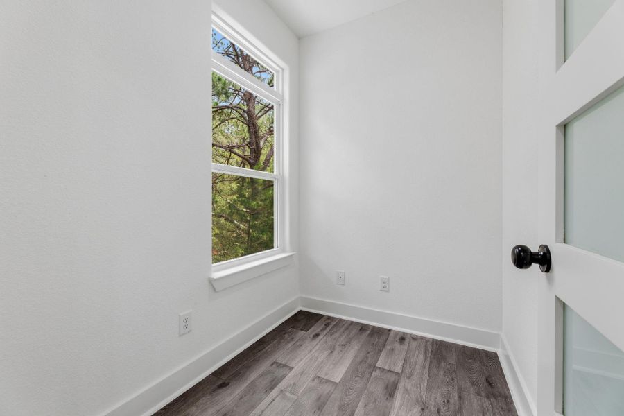 A quiet room featuring wood flooring and a window with vibrant outdoor views.