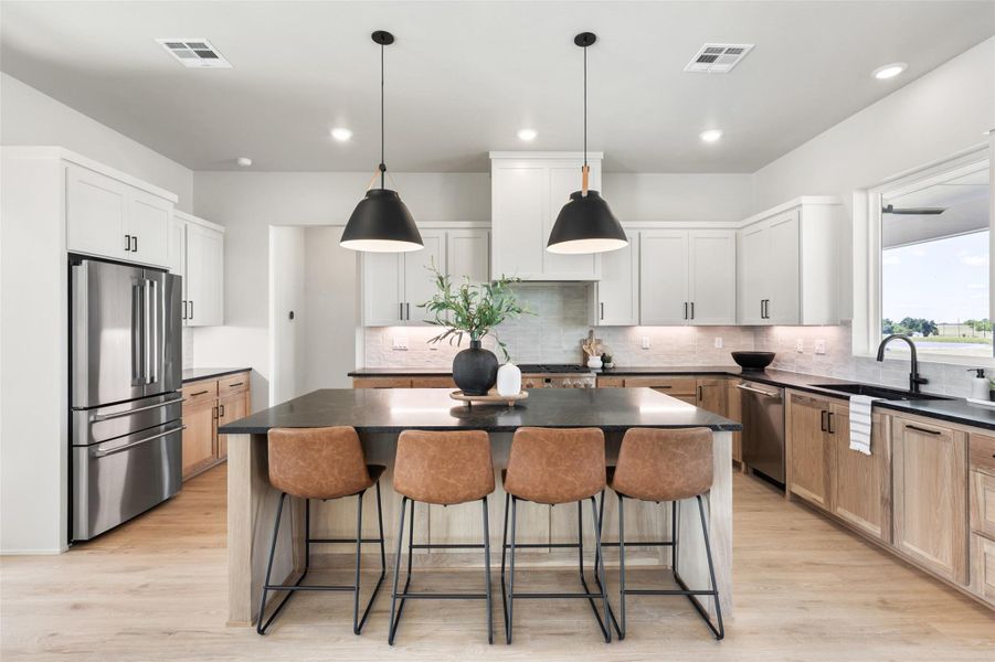 Kitchen featuring stainless steel appliances, a sink, dark countertops, a center island, and a breakfast bar Kitchen featuring stainless steel appliances, a sink, dark countertops, a center island, and a breakfast bar