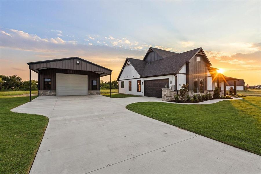 View of front of property with board and batten siding, a front lawn, a garage, and stone siding