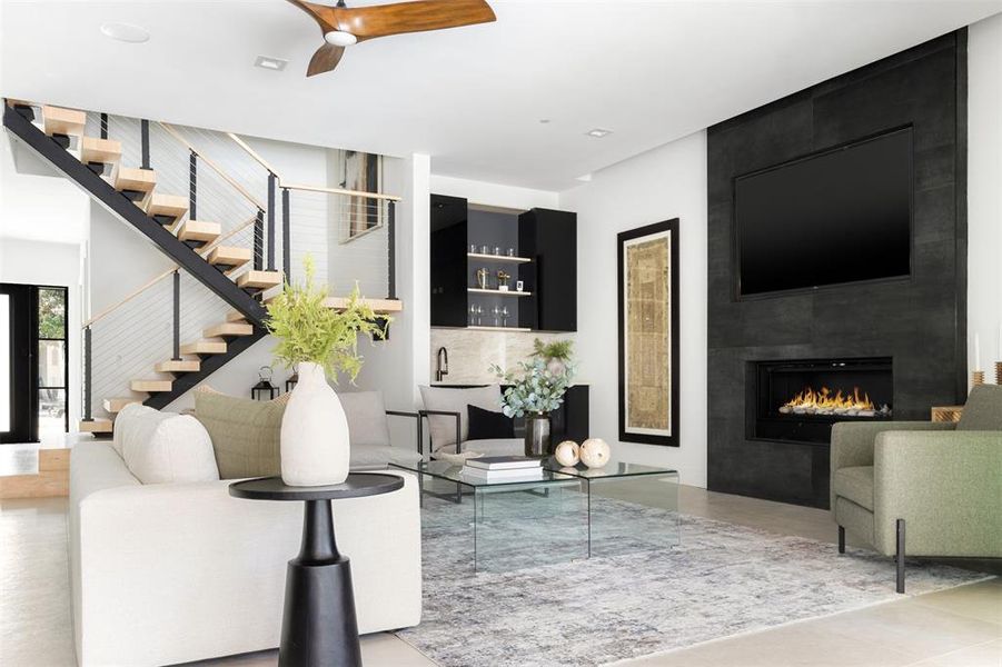 Living room featuring a large fireplace, sink, and ceiling fan