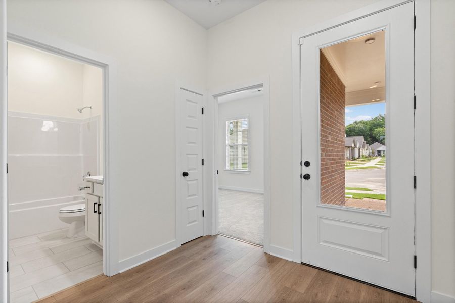 Entryway featuring wood-finish flooring, a white paneled door with a full-length glass insert, and matte black hardware Entryway featuring wood-finish flooring, a white paneled door with a full-length glass insert, and matte black hardware