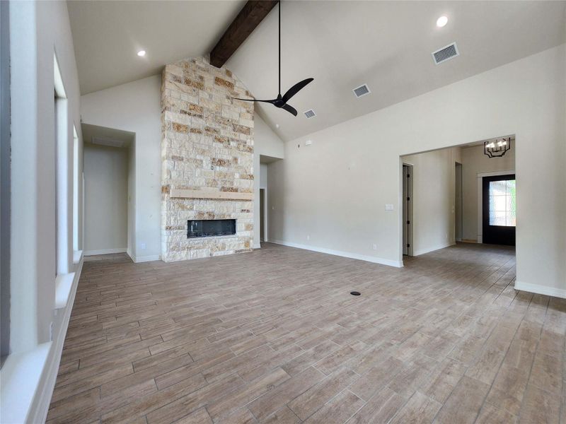 Unfurnished living room featuring ceiling fan, light wood-style flooring, a fireplace, and a chandelier