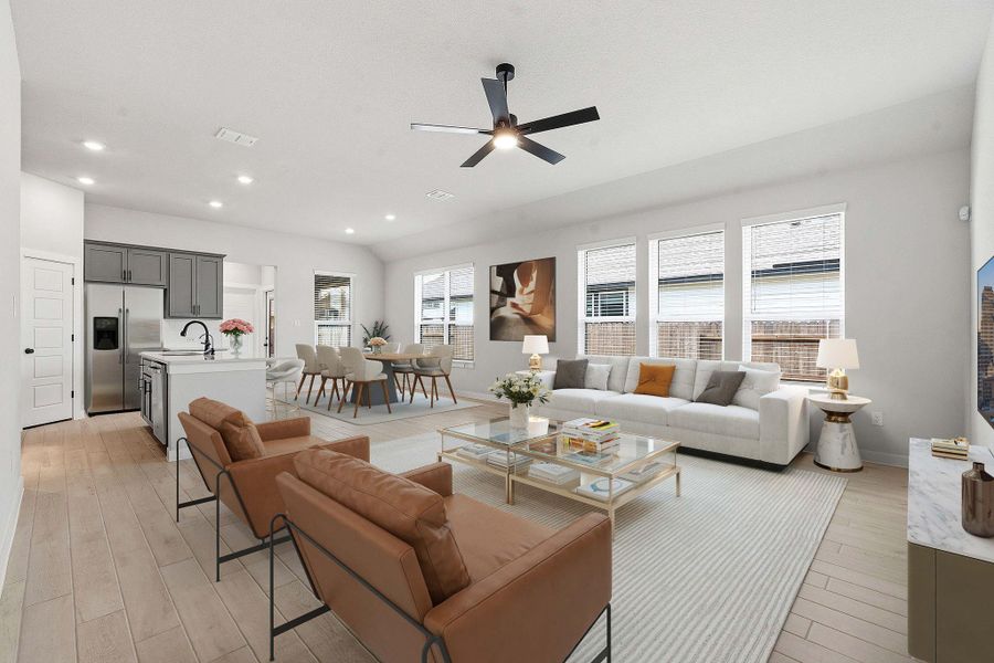 An open-concept interior features wood flooring, recessed lighting, and a modern ceiling fan.