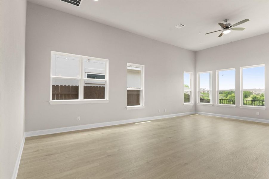 Empty room with ceiling fan, light wood finished floors, and baseboards
