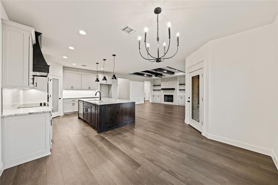 Kitchen with open floor plan, white cabinets, recessed lighting, decorative light fixtures, and light stone countertops
