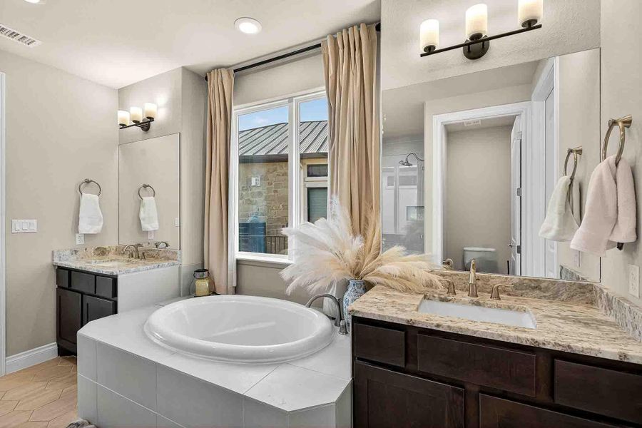 Bathroom featuring a garden tub, two vanities, and recessed lighting