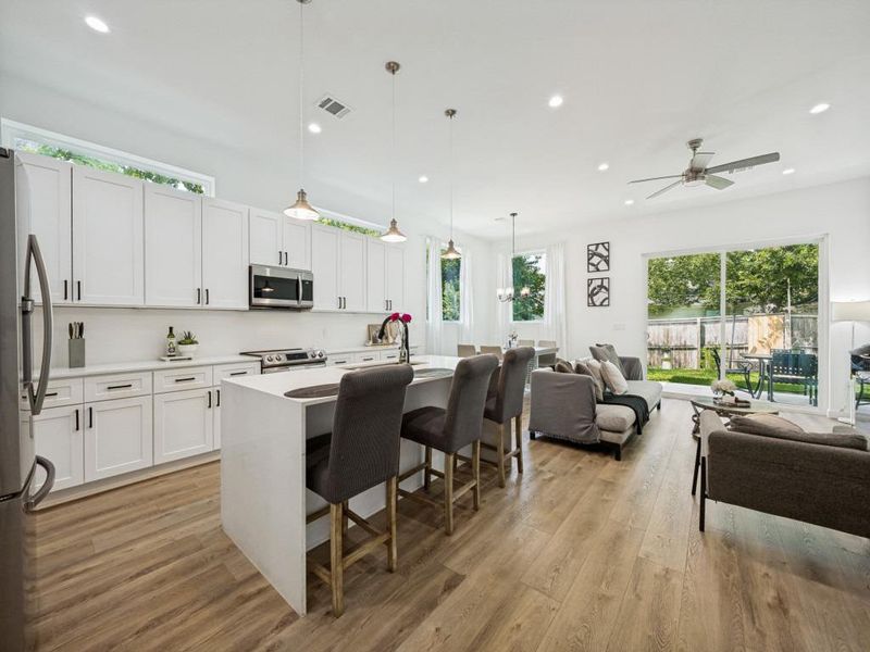 An open concept living area features a modern kitchen island with breakfast bar seating and direct access to a private yard. An open concept living area features a modern kitchen island with breakfast bar seating and direct access to a private yard.