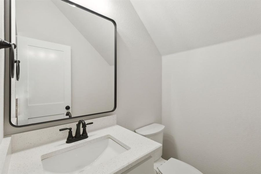 Bathroom featuring a vanity with an integrated sink, a speckled countertop, and a matte black faucet