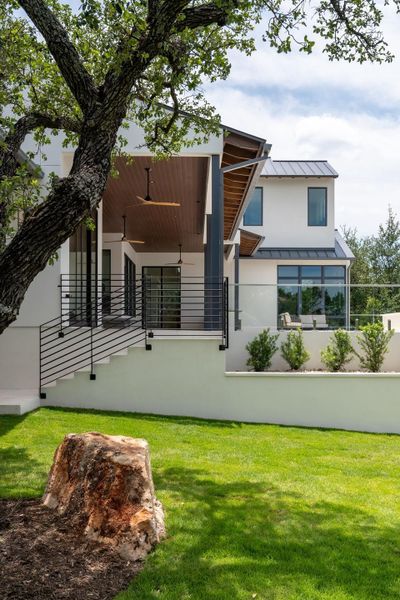 A modern architectural gem showcases a well-manicured lawn and a spacious outdoor patio, ideal for relaxation.