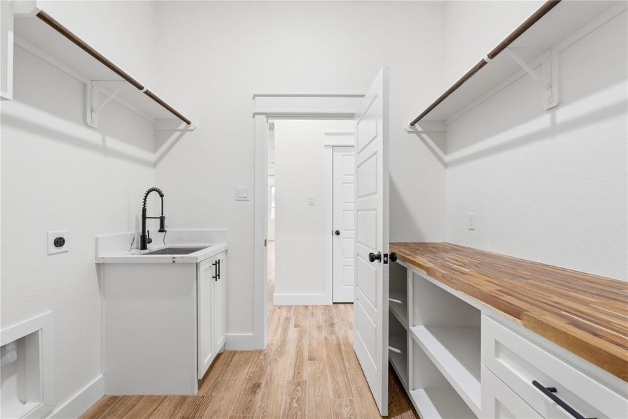 From the garage, you’ll step into a spacious laundry/mud room offering ample storage, a sink, and a dedicated folding area with plenty of storage.