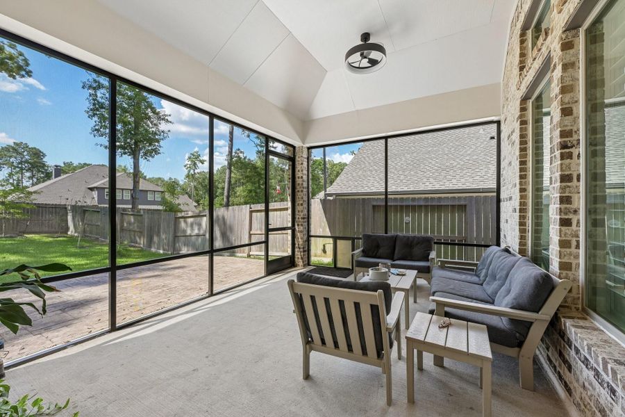 Screened in back patio with dog door and additional patio extending into the backyard