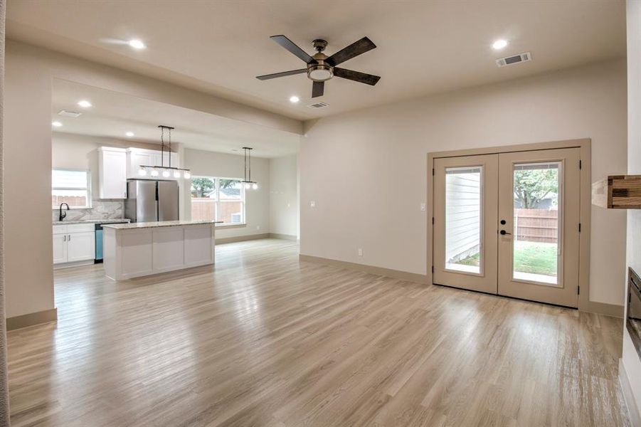 Unfurnished living room featuring light wood finished floors, recessed lighting, ceiling fan, and french doors
