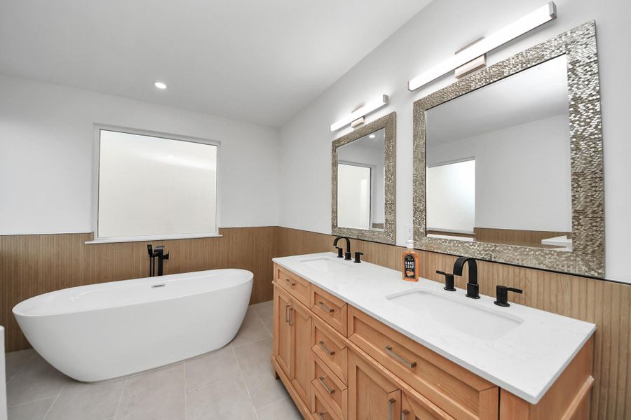 Double vanity with a quartz countertop, stylish mirrors, and sleek light fixtures. Double vanity with a quartz countertop, stylish mirrors, and sleek light fixtures.