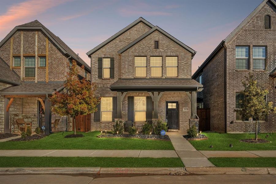 View of front of property featuring a front yard, brick siding, a porch, and a shingled roof