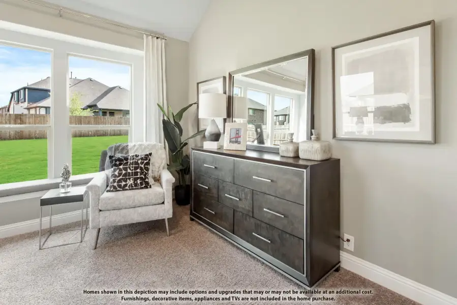 Bedroom sitting area with dark wood dresser, accent chair, and large windows overlooking backyard