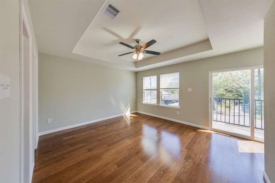 Step into a bright and inviting Master Bedroom featuring elegant engineered flooring and a stylish tray ceiling with a ceiling fan, adding both charm and comfort. Enjoy direct access to your private balcony, perfect for relaxing outdoors or taking in the fresh air."