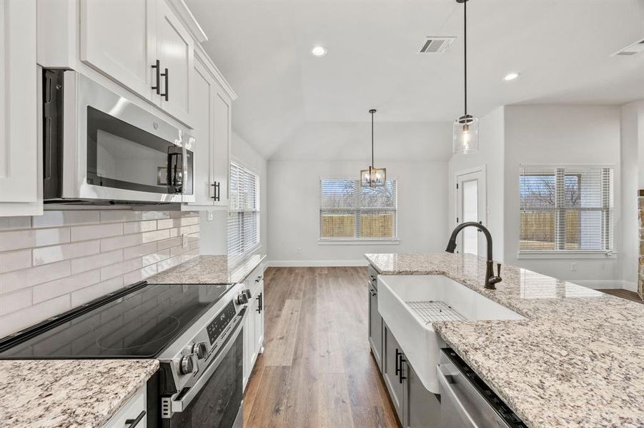 Kitchen featuring stainless steel appliances, light stone counters, light wood-type flooring, white cabinetry, and recessed lighting