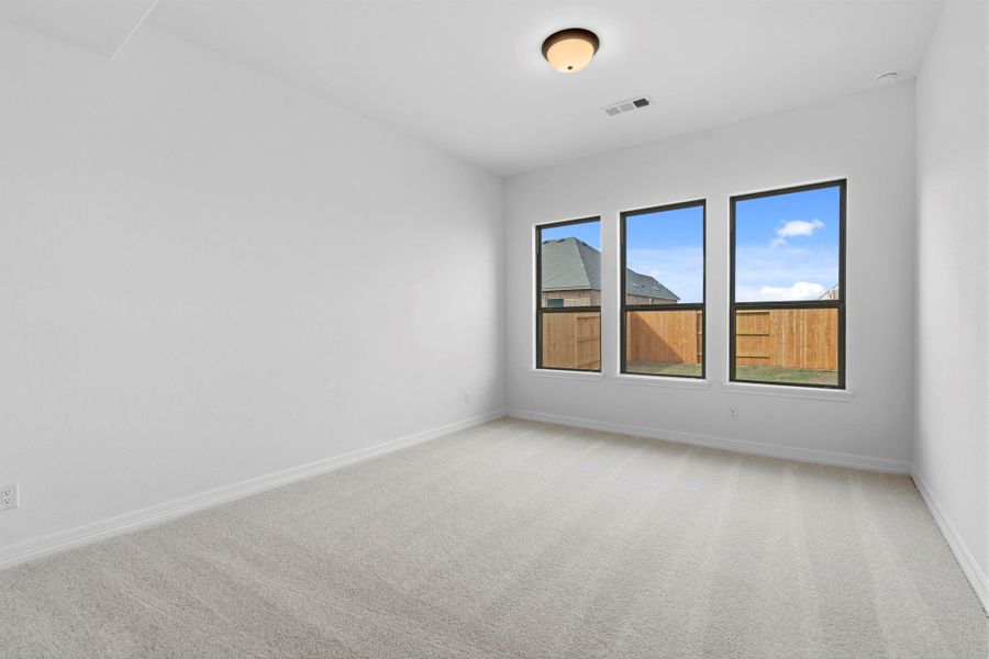 Serene primary suite with plush carpet and large windows—your perfect retreat to relax.
