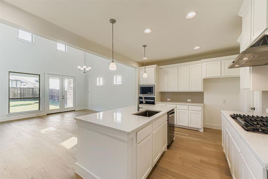 Kitchen featuring white cabinetry, recessed lighting, light wood-style flooring, hanging light fixtures, and a kitchen island with sink Kitchen featuring white cabinetry, recessed lighting, light wood-style flooring, hanging light fixtures, and a kitchen island with sink
