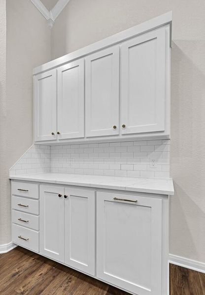 Detailed view of crown molding, tasteful backsplash, and wood finished floors
