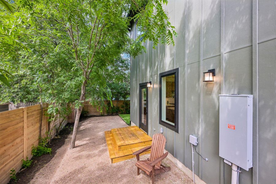 A private, fenced outdoor space with natural landscaping, a wood deck, and modern exterior lighting. A private, fenced outdoor space with natural landscaping, a wood deck, and modern exterior lighting.